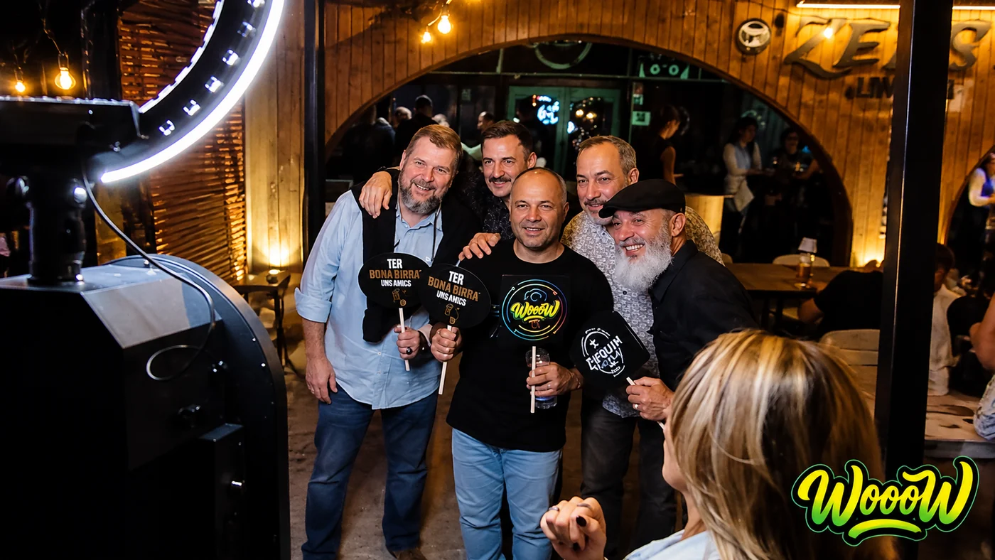 Grupo de amigos posando con carteles de atrezzo ante el fotomatón de WooW en una fiesta nocturna en Mallorca